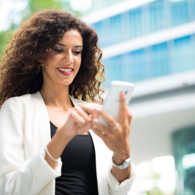 A woman ordering a service on her cell phone with an office building in the background